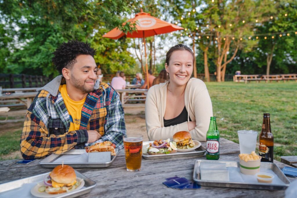 Friends sharing burgers and drinks at a picnic table in the Boonedogs yard